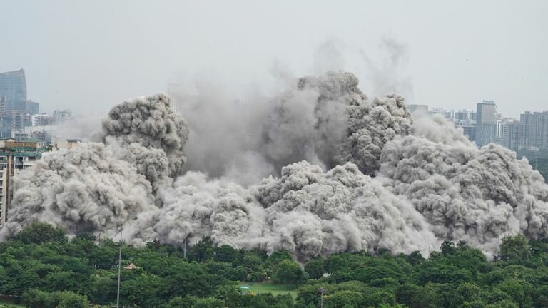 A cloud of dust rises as twin high-rise apartment towers flatten. Photo: AP