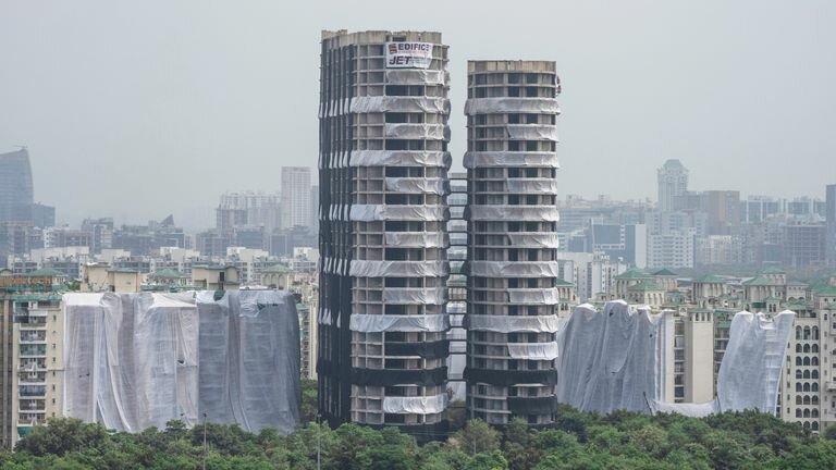 The twin high-rise towers are visible even before they are razed to the ground. Photo: AP